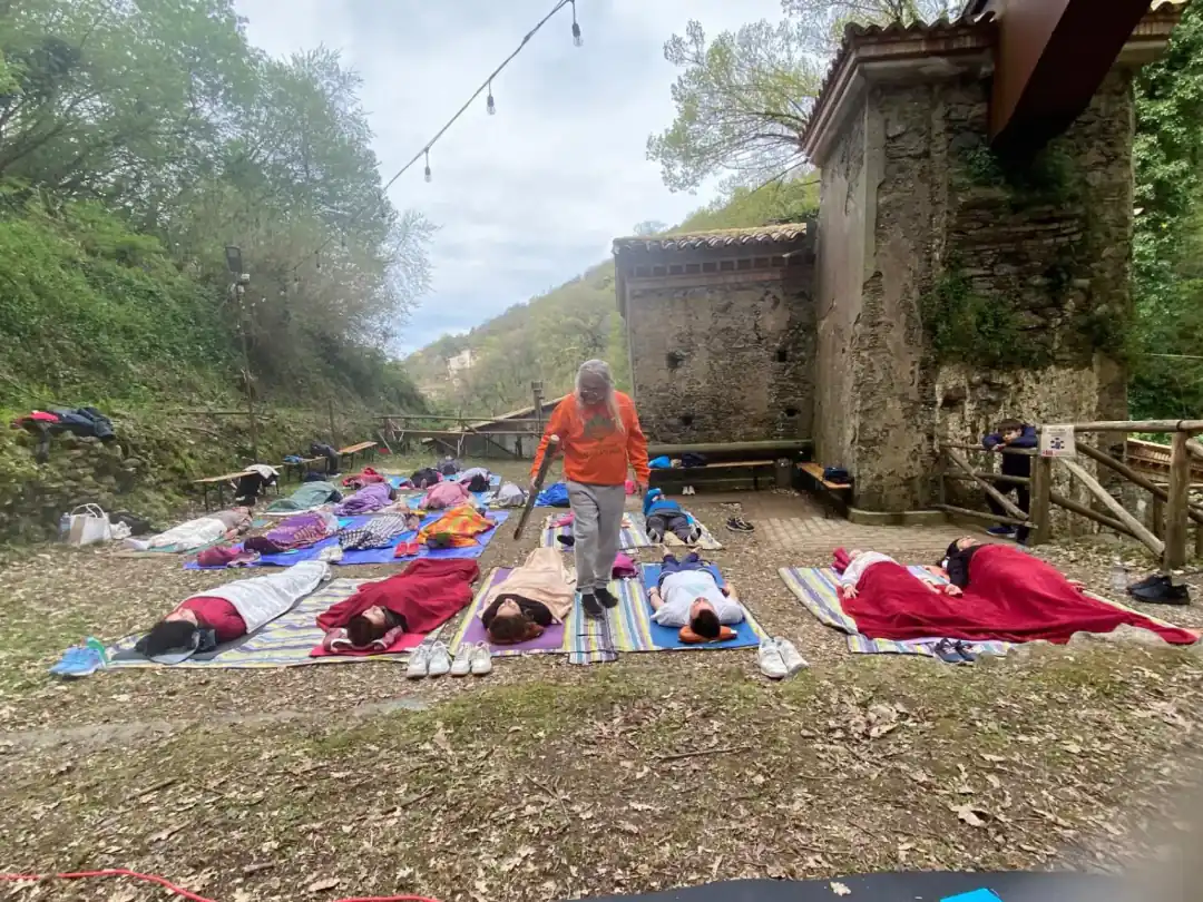 Incontro all'aperto dell'Associazione Dharmonia: i partecipanti distesi su coperte mentre un socio suona le campane tibetane